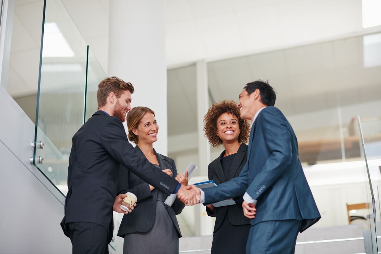 smiling business people shaking hands in office