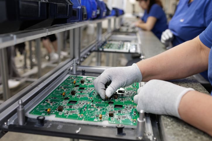 Gloved technician assembling PCB