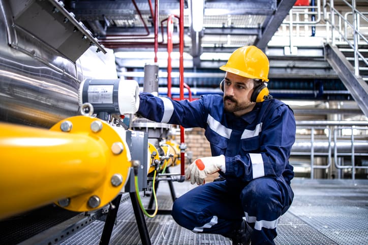 Worker inspecting industrial equipment in a factory