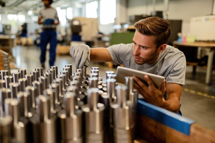 Young steel worker performing quality control of manufactured products