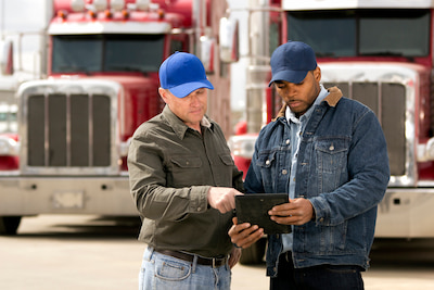 two workers standing in front of two semi trucks